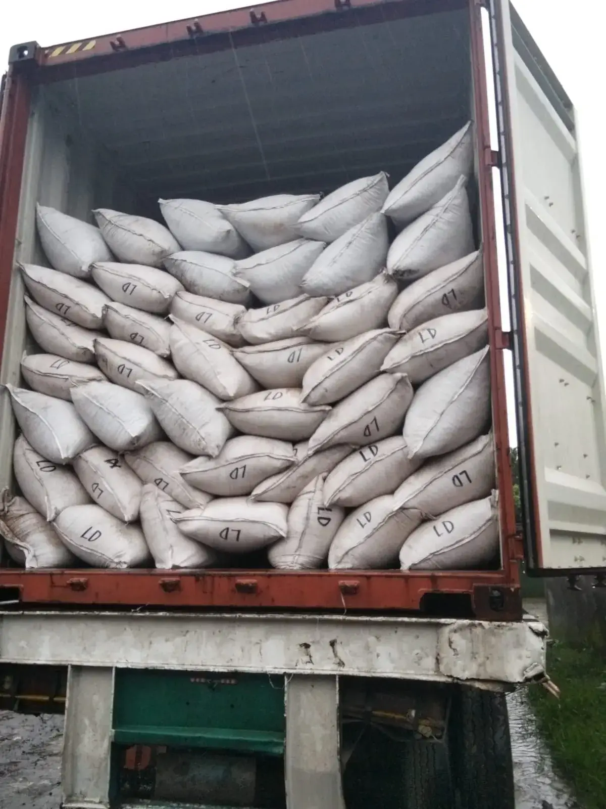 A container loaded with filled sacks, doors open on the trailer.
