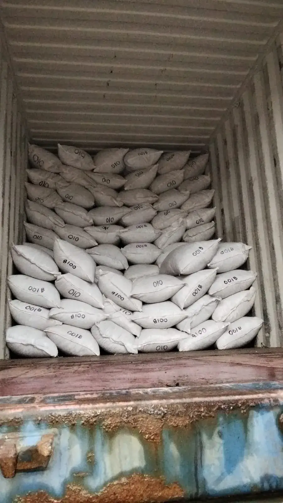 Sacks marked with their lot codes, stacked inside a container.